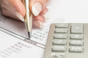 Hand holding pen entering information from calculator